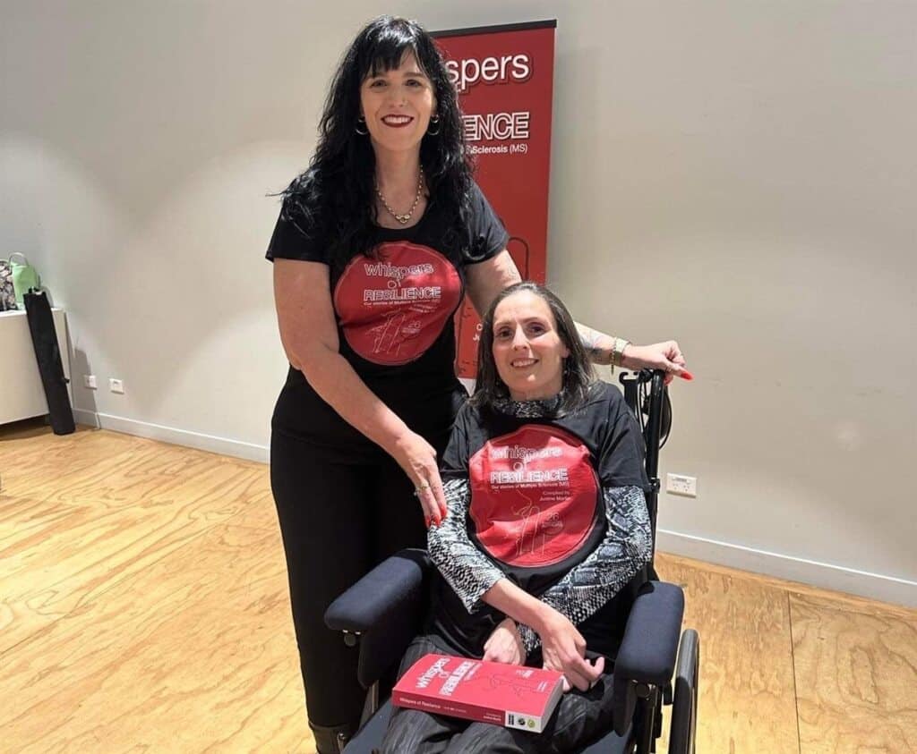 A woman stands next to and smiles at a disabled man in a wheelchair.